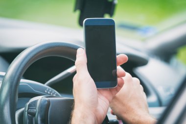 Arabada akıllı telefon olan adam