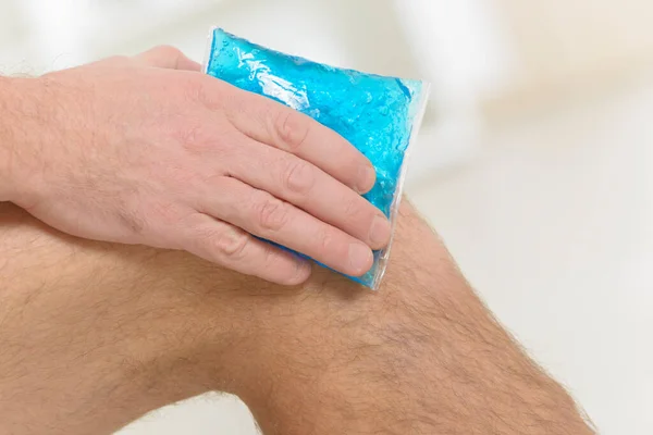 Man using cold gel compress on knee to reduce pain