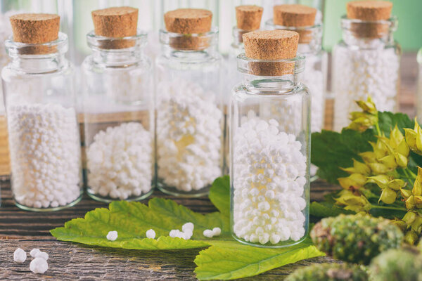 Homeopathic lactose sugar globules in glass bottles with plants