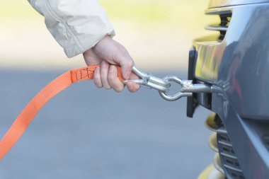 Bozuk bir arabaya halat bağlayan kadın.