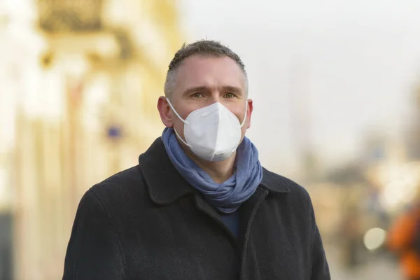 防御用の抗ウイルスマスクをした男が街の通りを歩く — ストック写真