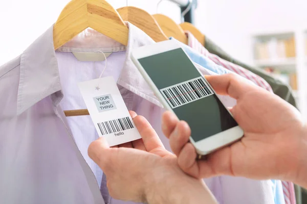 Woman scanning bar code from a label in a shop with mobile phone