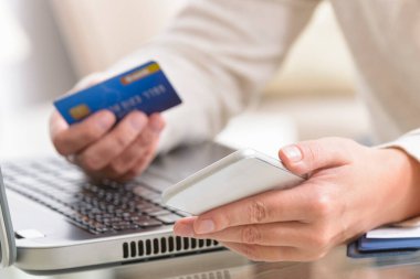 Bir kadının kredi kartı ve akıllı telefonunu defterin üzerinde tutuyor ve bunu internet üzerinden ödeme yapmak için kullanıyor. E-posta konsepti ve internet üzerinden ödeme.