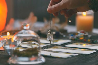 Falcı tarot kartlarının üzerinde sarkacı tutuyor.