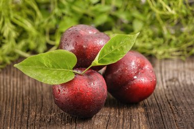 Tahtada yeşil yapraklı üç kırmızı erik