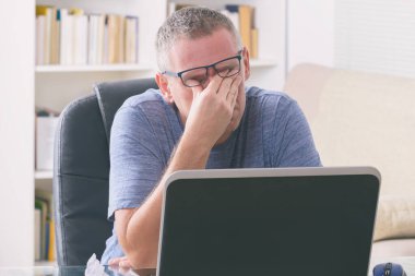 Dizüstü bilgisayarla uğraşırken gözünü ovmaktan yorgun düşmüş.