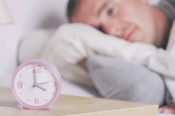 男人试图在晚上睡觉 闹钟在前景是可见的 失眠的概念 — 图库照片