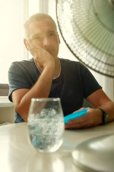 Uomo Soffre Calore Mentre Seduto Sala Cerca Rinfrescarsi Dal Ventilatore — Foto Stock