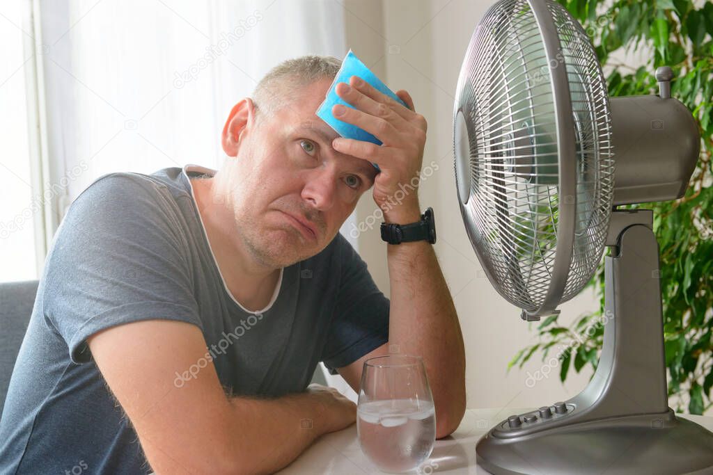 Man suffers from heat at home and tries to cool off by the fan