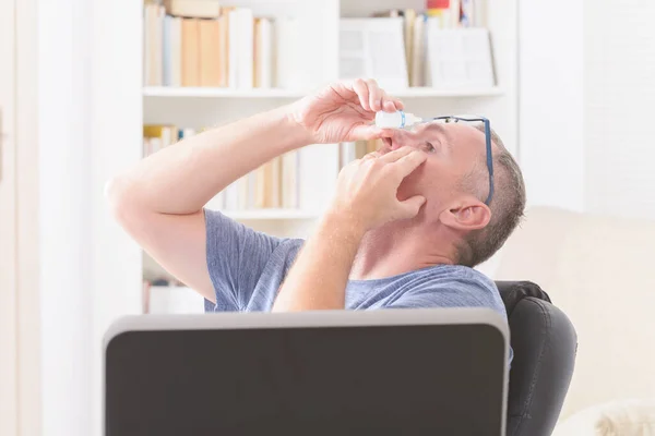 Man Die Oogdruppels Aanbrengt Een Lange Zit Achter Computer Stockafbeelding