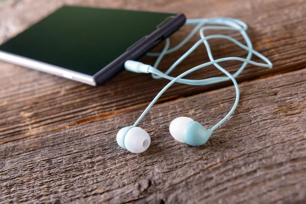 Small headphones with mobile phone — Stock Photo, Image