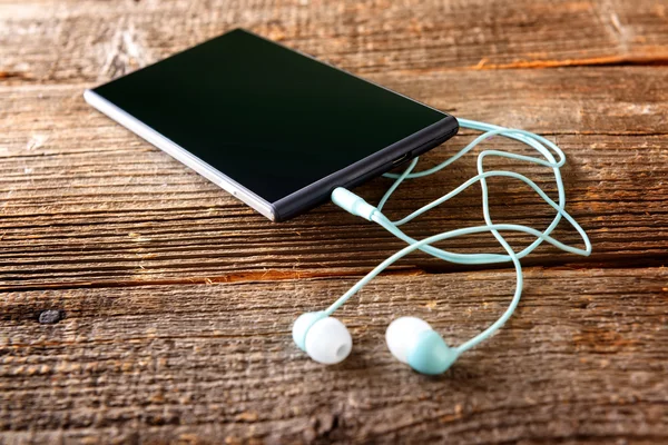 Small headphones with mobile phone — Stock Photo, Image