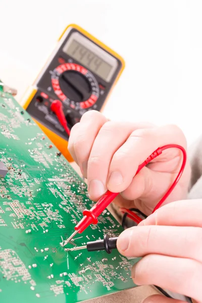 Serviceman checks PCB with a digital multimeter — Stock Photo, Image