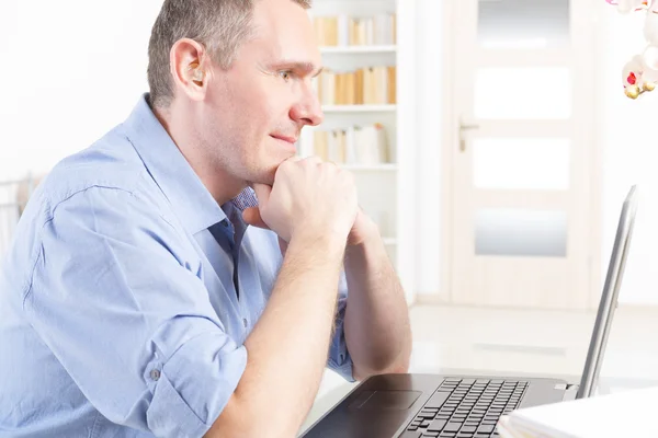 Hearing impaired man working with laptop — Stock Photo, Image