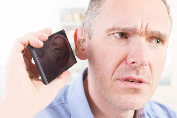 Человек с нарушением слуха с помощью мобильного телефона — стоковое фото