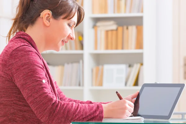 Hearing impaired woman working with tablet — Stock Photo, Image