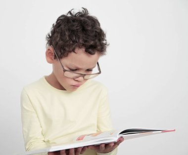 Okulda eğitim kitabına bakan çocuk, insanların resimli fotoğraflarına şaşırmış gibi davranıyor.