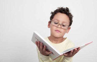 Okulda eğitim kitabına bakan çocuk, insanların resimli fotoğraflarına şaşırmış gibi davranıyor.