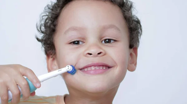 boy brushing his teeth with an electric tooth brush on white background stock photo