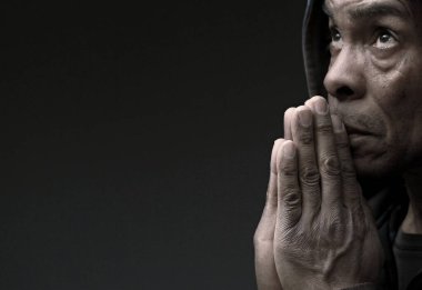 dindar kıdemli Karayipli adam stüdyoda karanlık arka plan için dua ediyor.