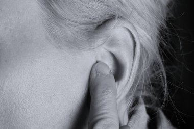 Gri arka planda sağırlık ve işitme kaybı yaşayan kadın.