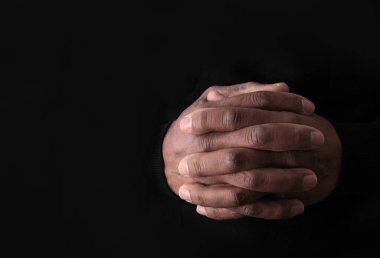 İncil 'i okuduktan sonra Tanrı' ya el ele dua ediyoruz. Siyah arka planda dua ediyoruz.