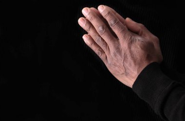 İncil 'i okuduktan sonra Tanrı' ya el ele dua ediyoruz. Siyah arka planda dua ediyoruz.