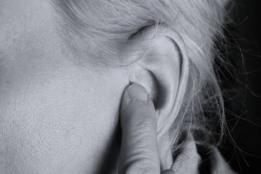 Gri arka planda sağırlık ve işitme kaybı yaşayan kadın.