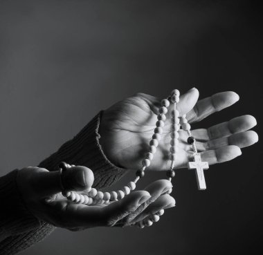 Elinde haçla tespih taşıyan birinin siyah beyaz fotoğrafı..