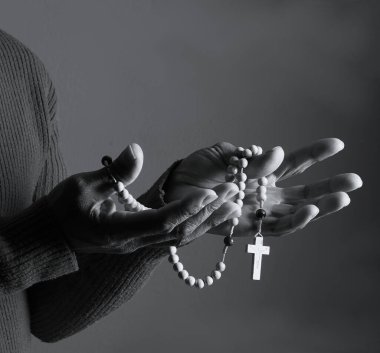 Elinde haçla tespih taşıyan birinin siyah beyaz fotoğrafı..