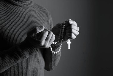 Elinde haçla tespih taşıyan birinin siyah beyaz fotoğrafı..