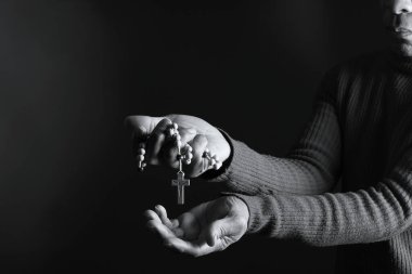 Elinde haçla tespih taşıyan birinin siyah beyaz fotoğrafı..