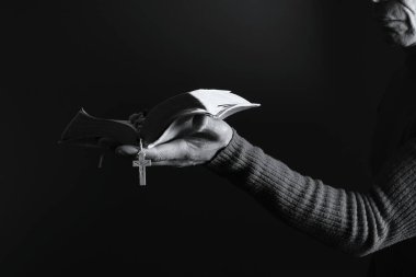 İncille ve haçla tespih çeken kişi..