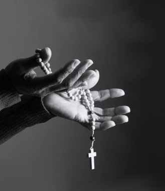 Elinde haçla tespih taşıyan birinin siyah beyaz fotoğrafı..