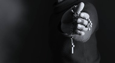 Elinde haçla tespih taşıyan birinin siyah beyaz fotoğrafı..