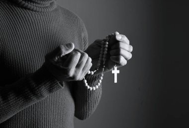 Elinde haçla tespih taşıyan birinin siyah beyaz fotoğrafı..