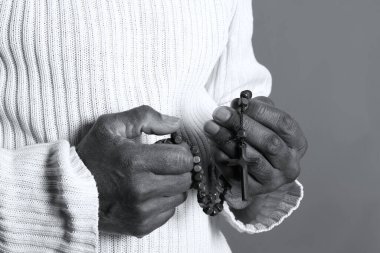 Elinde haçla tespih taşıyan birinin siyah beyaz fotoğrafı..