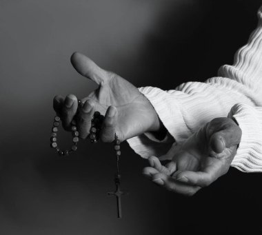Elinde haçla tespih taşıyan birinin siyah beyaz fotoğrafı..