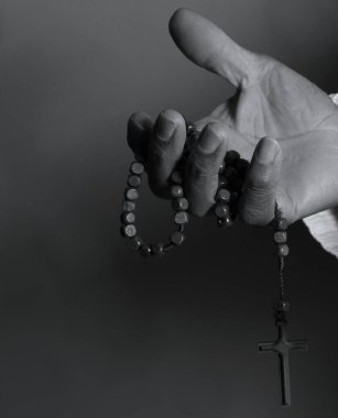 Elinde haçla tespih taşıyan birinin siyah beyaz fotoğrafı..