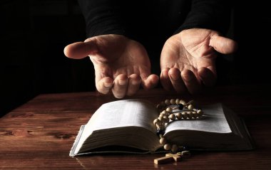 Adam tespih ve incil ile dua ediyor.