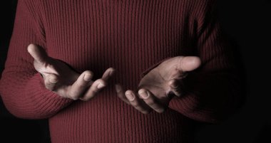 Elleri açık, siyah arkaplana karşı duygularını ifade eden kişi