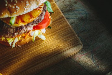 Tahta masada ananaslı Lezzetli Burger manzarası, karamsar ışıklandırma..