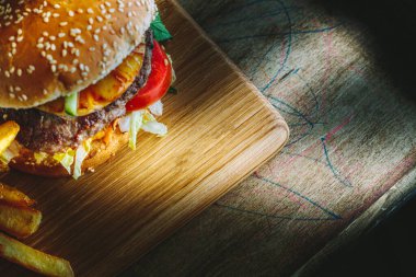 Tahta masada ananaslı Lezzetli Burger manzarası, karamsar ışıklandırma..