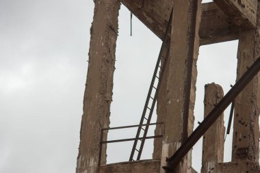 Evin arka planında paslı metal vinç var..