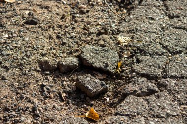 Kırık asfalt ve küçük taşlar.