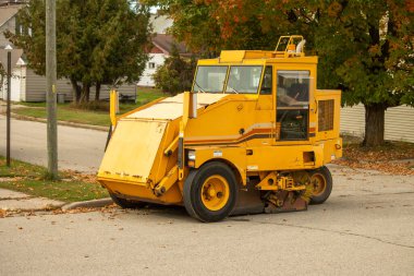 Sokakları süpüren sarı bir sokak süpürücüsü