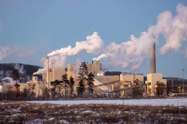 Küçük bir fabrikada büyük bir beyaz buhar sütunu..