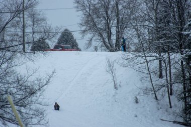 Çocuklar kışın tepeden aşağı kayıyor.