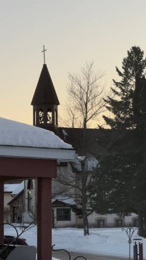 Kış günbatımında karlı bir kasabada bir mahalle kilisesi.