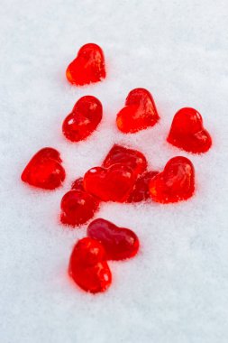 Kış günü kar üzerinde parlak kırmızı cam kalpler, aşk sembolü, Sevgililer Günü tatili konsepti.